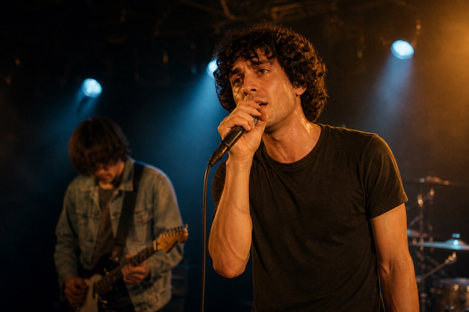 Close stage shot of the same singer in a dark t-shirt at the microphone